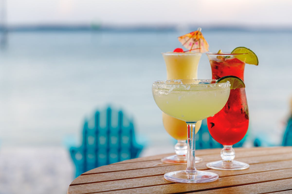 three cocktails on a table on the beach