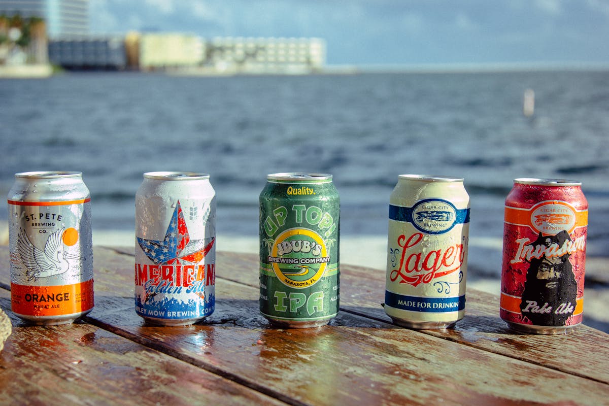 three beer cans on a table by the water