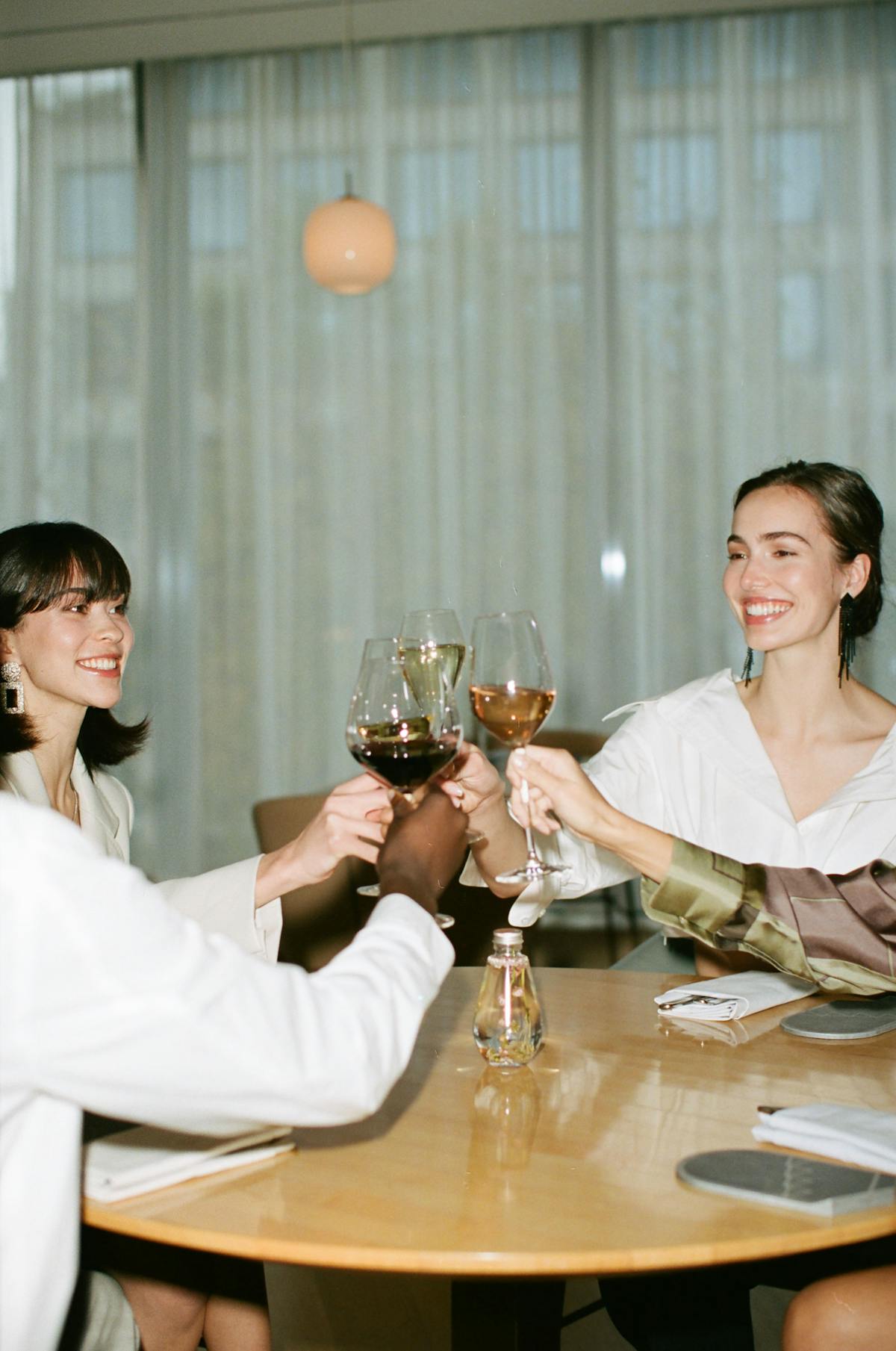Four people sitting at a table cheersing glasses of wine