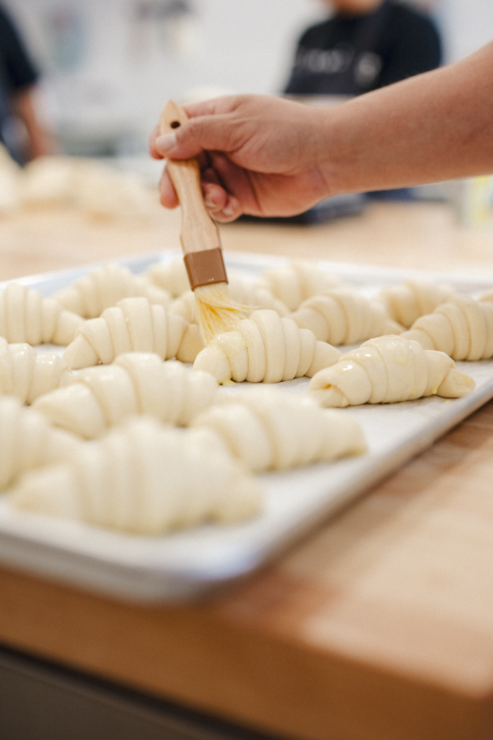 a person holding a brush over croissants