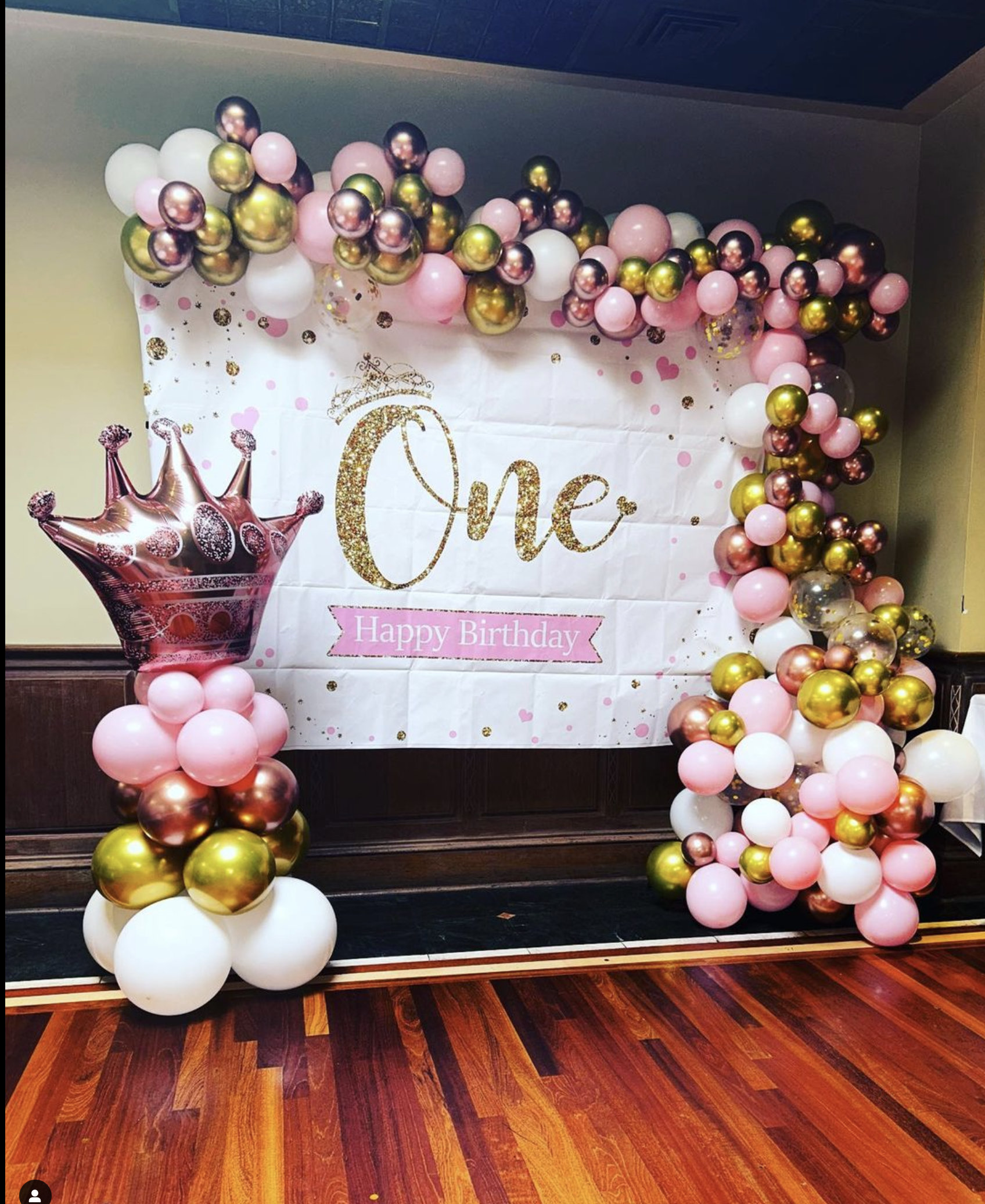 a balloon arch with a crown and a banner