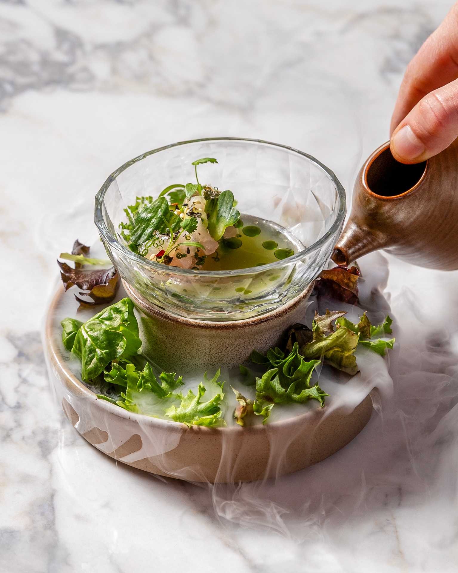 a hand pouring a bowl of soup