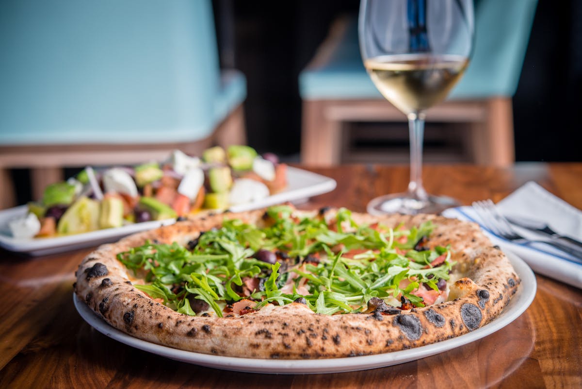 a pizza with a wine glass on a table