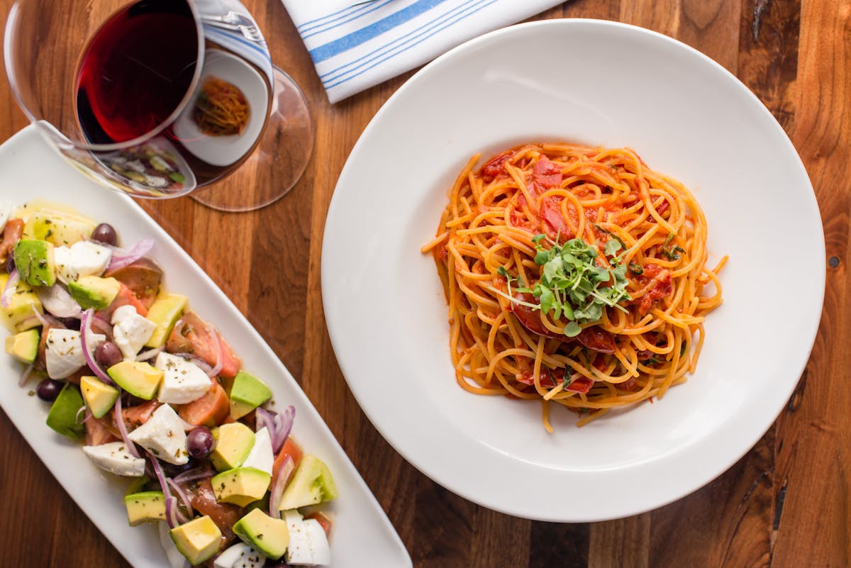 an spaghetti and salad plate in a table