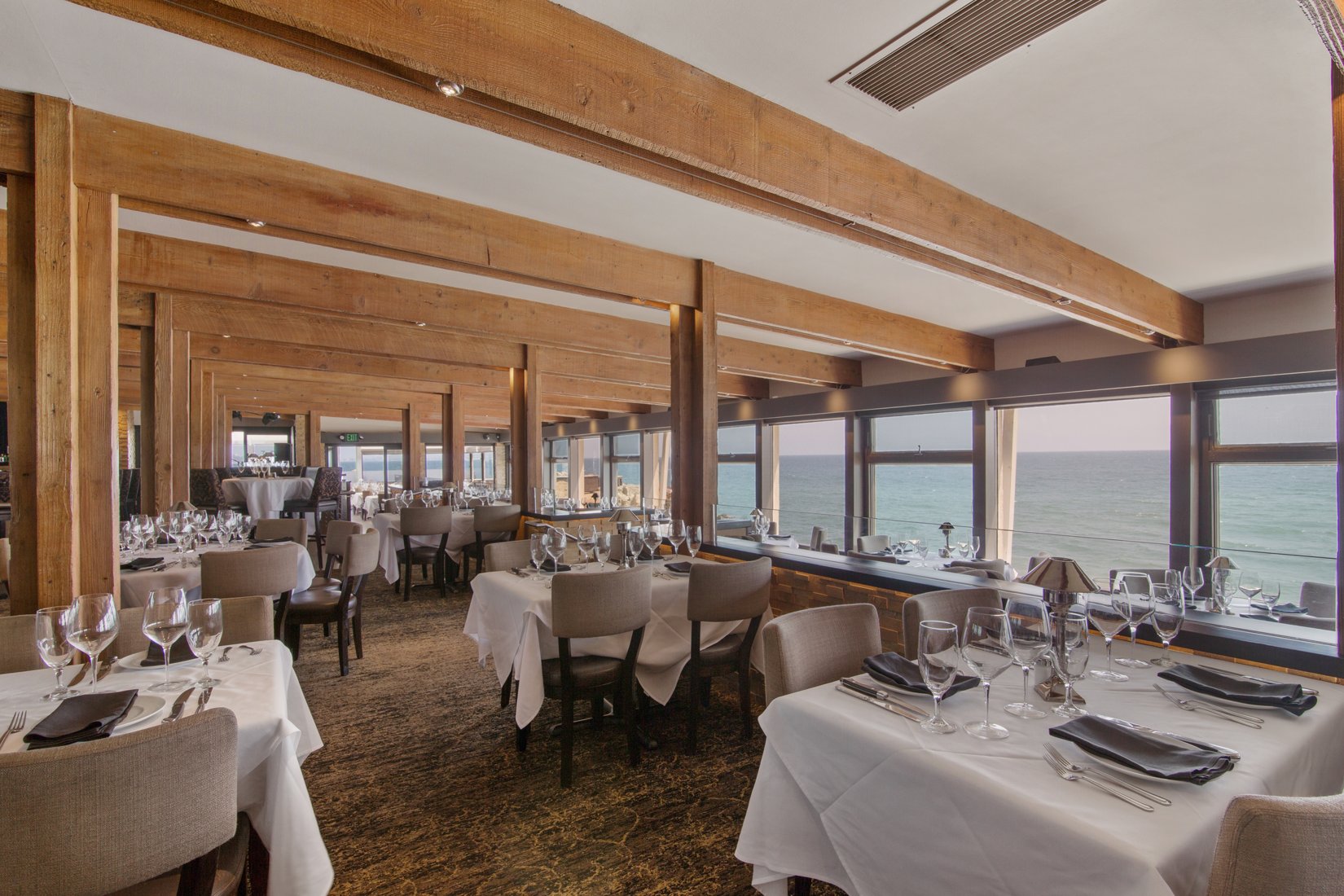 a room with tables and chairs and a view of the ocean