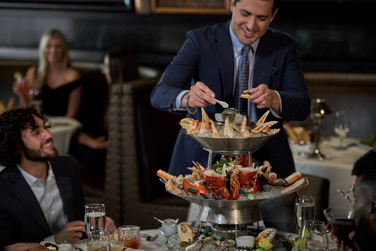 a man in a suit putting food on a tiered tray