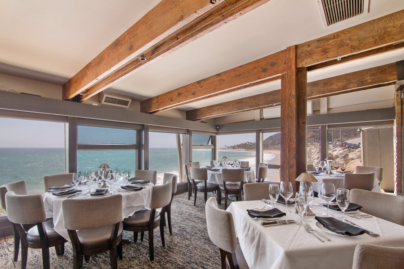 a room with tables and chairs and a view of the ocean