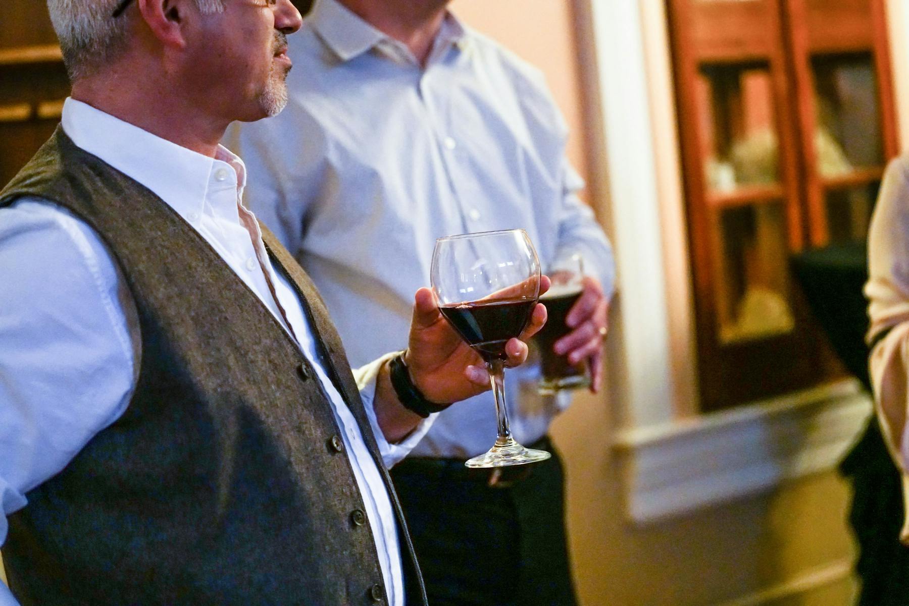 a man wearing a suit and tie holding a wine glass