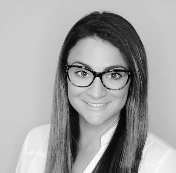 a woman wearing glasses and smiling at the camera