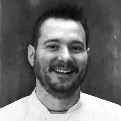 a man wearing a white shirt and smiling at the camera