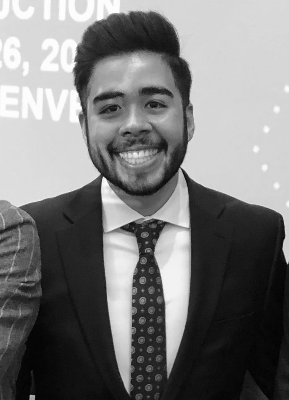 a man wearing a suit and tie smiling at the camera