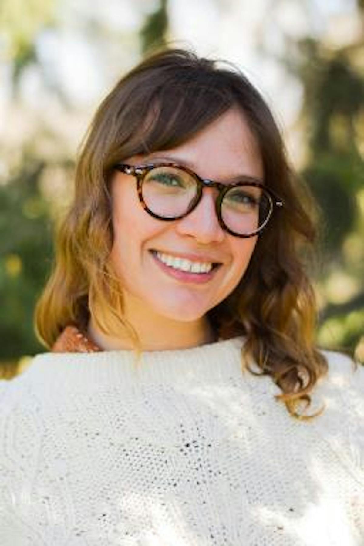 a woman wearing glasses and smiling at the camera