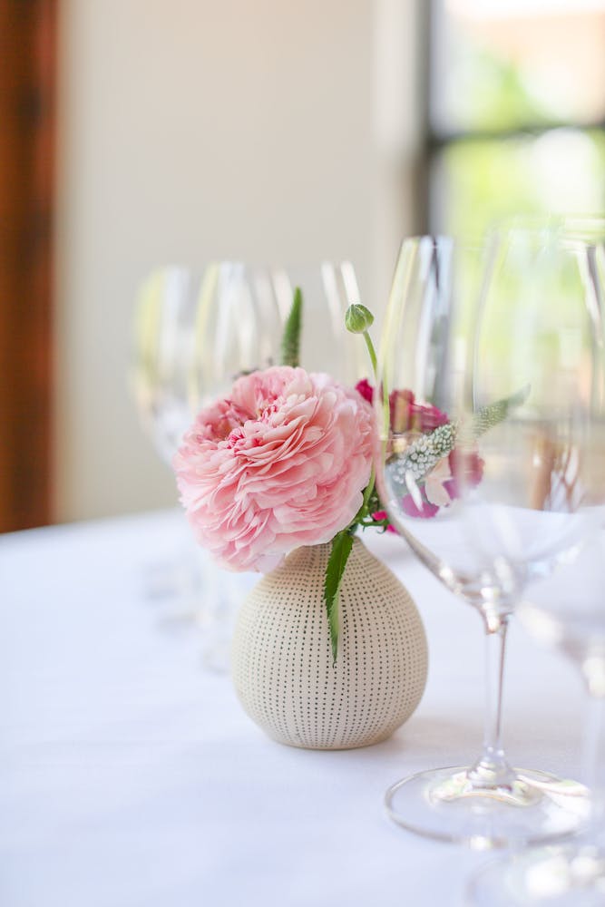 a close up of a glass vase on a table with wine glasses