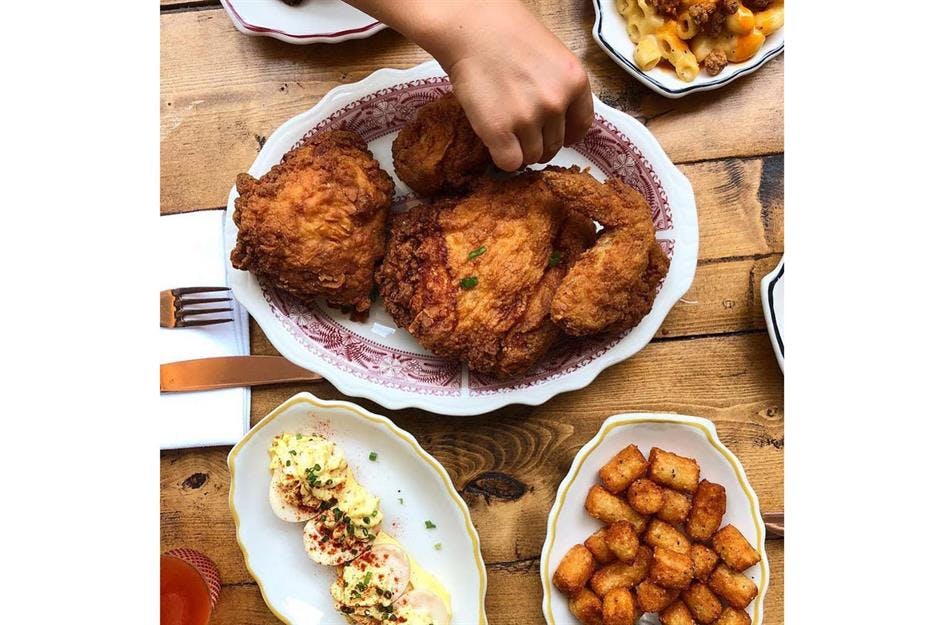 a person holding a plate of food on a table