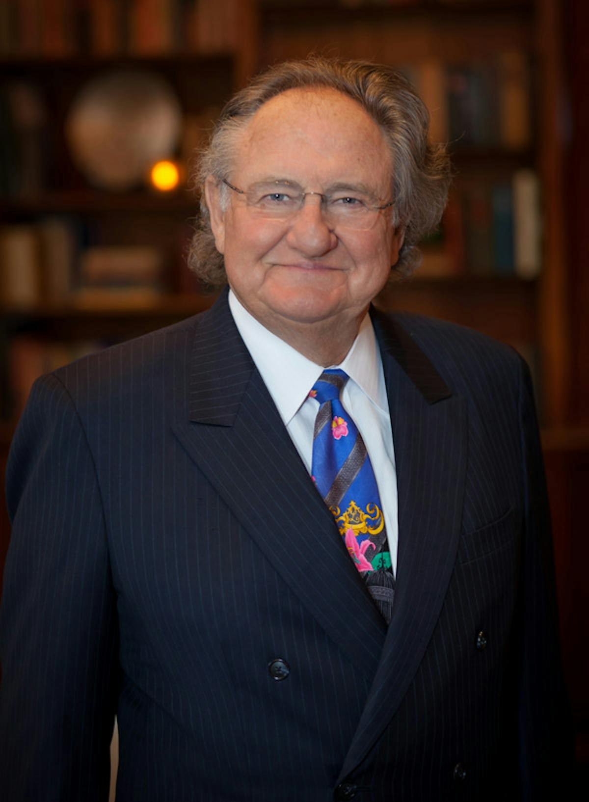 a man wearing a suit and tie smiling at the camera