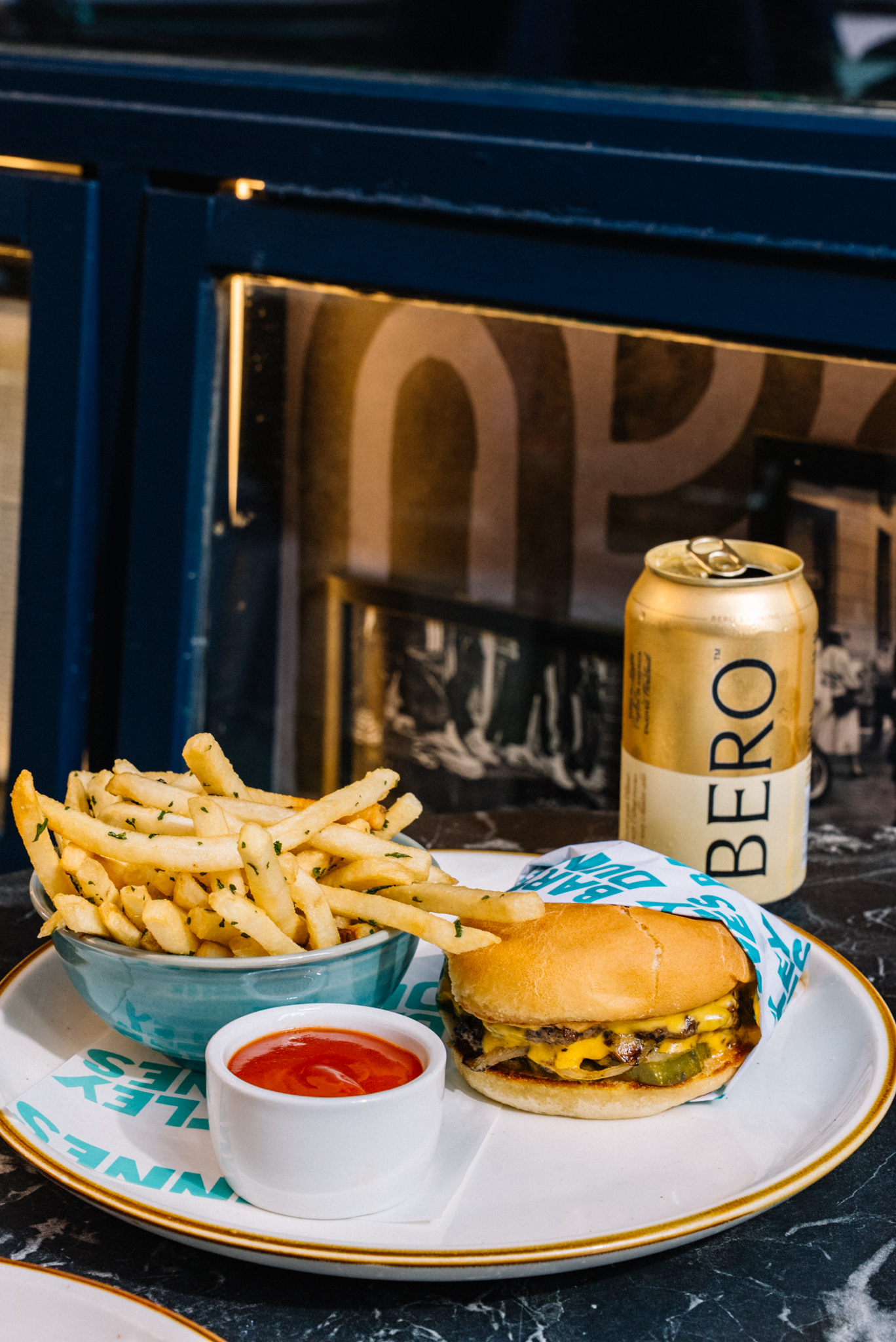 smashburger and fries with a bero non-alcoholic beer in the background